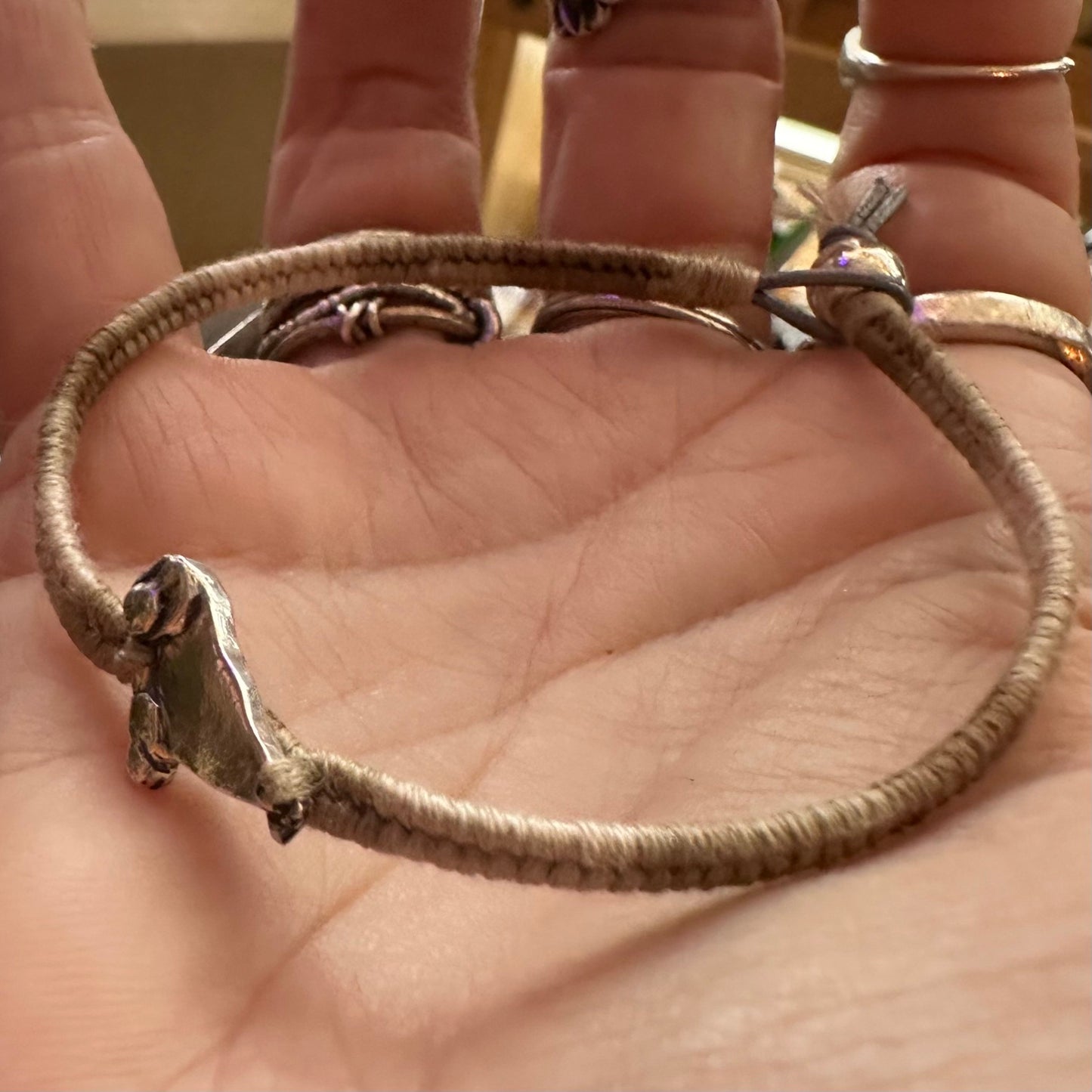 A beautiful beige leather, cotton and sterling silver friendship bracelet with a fine silver seal charm.