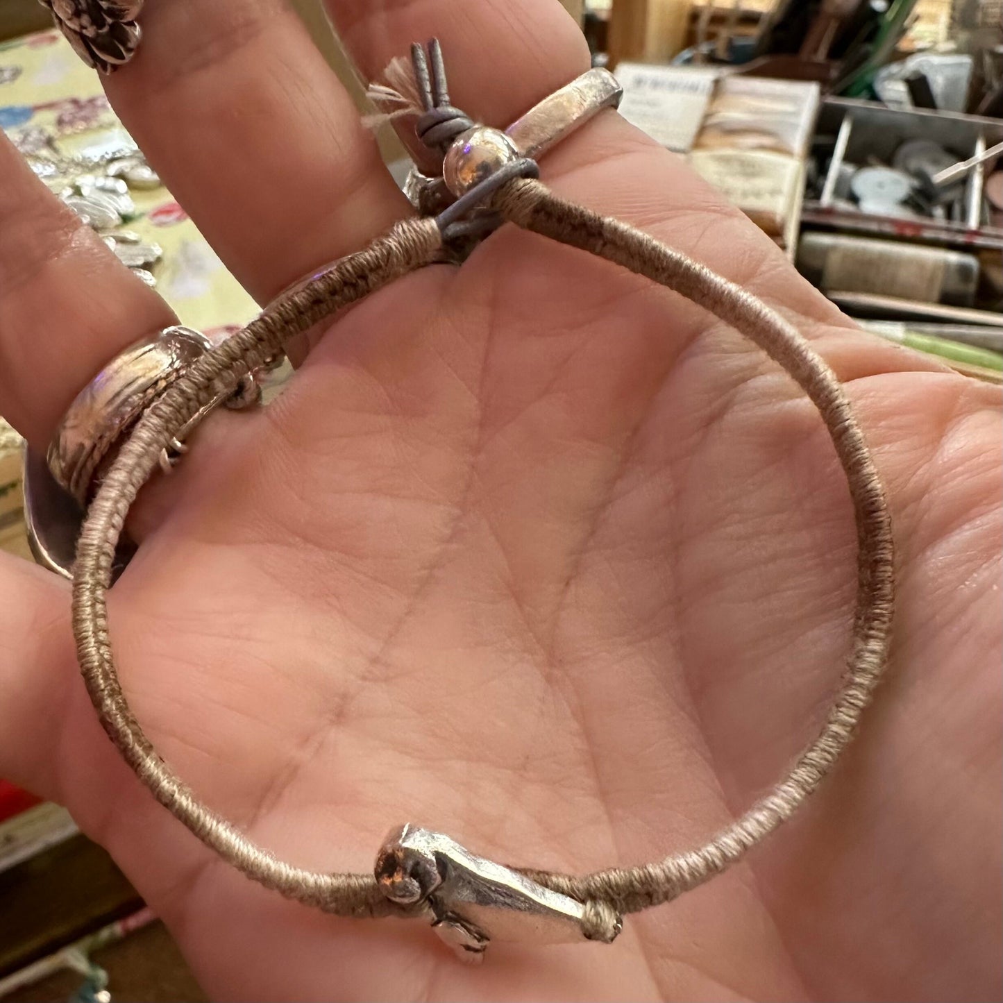 A beautiful beige leather, cotton and sterling silver friendship bracelet with a fine silver seal charm.