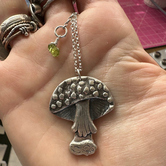 A gorgeous handmade fine silver mushroom toadstool pendant hung on a sterling silver chain.