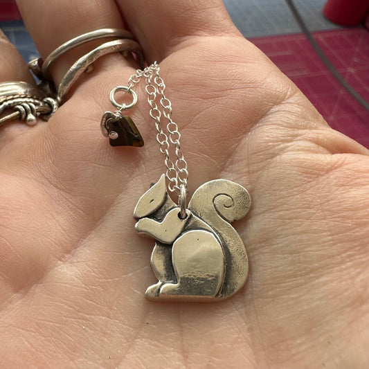 A beautiful handmade fine silver squirrel pendant on a sterling silver chain.