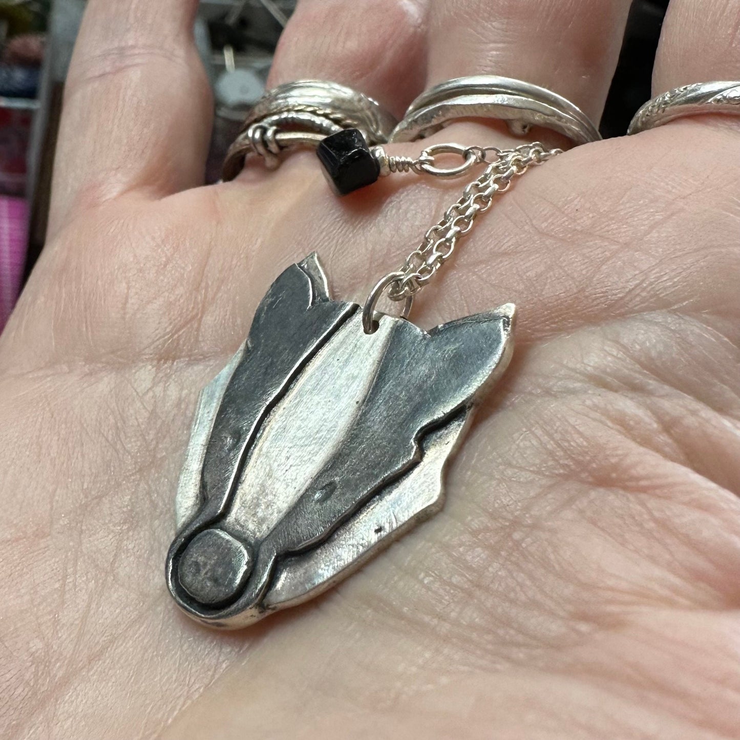 An adorable badger pendant, handmade in fine silver, hung on a sterling silver chain.