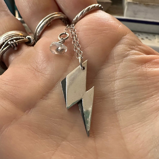 A beautiful simple lightning bolt pendant hand made in fine silver, hung on a sterling silver chain.