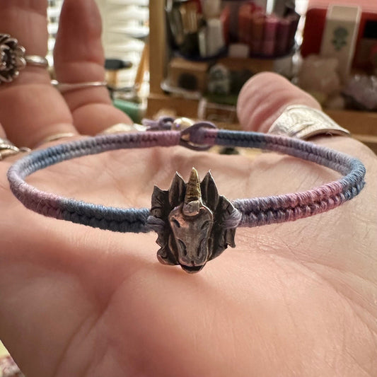 A beautiful little fine silver unicorn on a beautiful pinky purple leather, cotton and sterling silver woven charm bracelet.