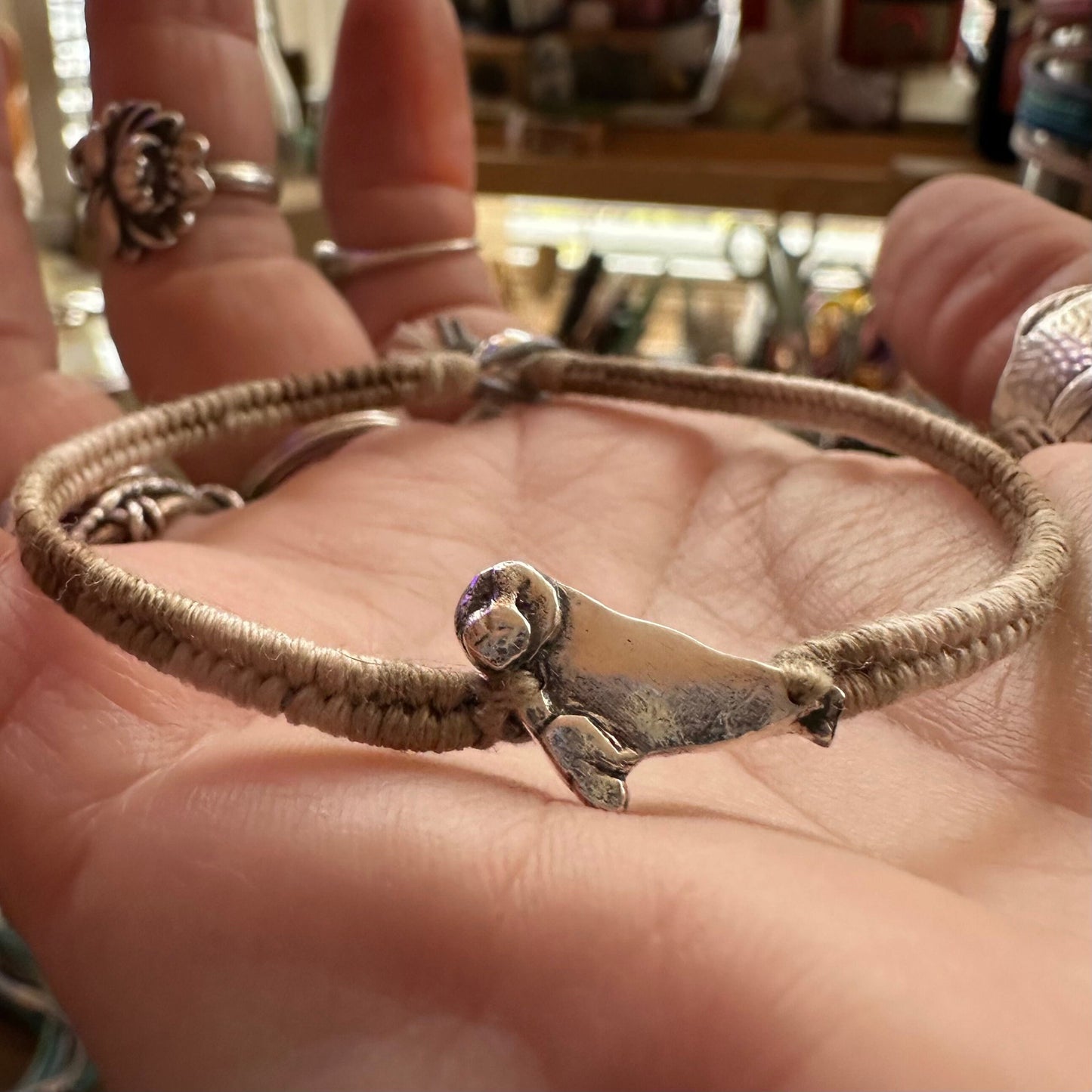 A beautiful beige leather, cotton and sterling silver friendship bracelet with a fine silver seal charm.