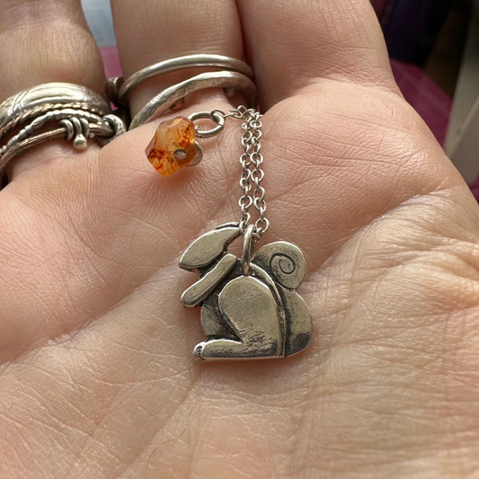 A beautiful tiny handmade fine silver squirrel pendant on a sterling silver chain.